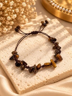 Bracelet MELLIA éclats œil de tigre 1 Bracelet MELLIA en éclats d’œil de tigre sur cordon marron, posé sur pierre claire – Serinaé