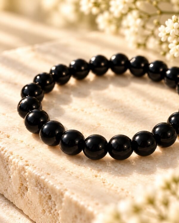 Détail des perles rondes d’obsidienne noire à la finition polie et brillante du bracelet NÉRA Noir Intense
