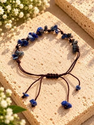 Bracelet sodalite – éclats Bracelet en éclats de sodalite sur cordon marron ajustable, posé sur une pierre