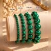 bracelets-malya-malachite-tailles Quatre bracelets MALYA en malachite naturelle de 4, 6, 8 et 10 mm présentés sur un coussin avec leurs tailles