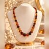collier ambrine perles ambrees degrade buste Collier AMBRINE en perles ambrées en dégradé, nuances miel, cognac et brun, porté sur buste crème – Serinaé