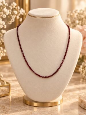 Collier GARANCE FINE en pierres rouges naturelles facettées de 2 mm, rouge bordeaux, porté sur buste crème – Serinaé