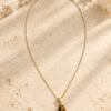 Collier médaillon MELLIA, cabochon rond en œil de tigre naturel sur fine chaîne plaquée or, posé sur pierre claire – vue 1