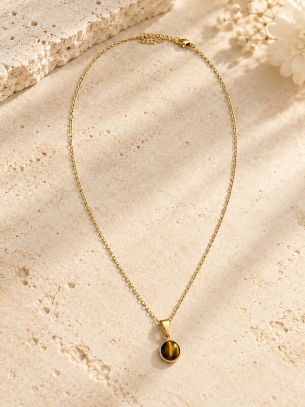 Collier médaillon MELLIA, cabochon rond en œil de tigre naturel sur fine chaîne plaquée or, posé sur pierre claire – vue 1