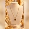 collier mellia goutte pendentif oeil de tigre buste Collier MELLIA GOUTTE, fine chaîne à billes aux finitions dorées et pendentif ovale aux nuances d'œil de tigre, sur buste crème – Serinaé