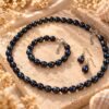 Parure ÉPURE Noire – perles d'eau douce noires 3 Collier, bracelet et boucles d'oreilles ÉPURE Noire en perles de culture d'eau douce noires posés sur une pierre